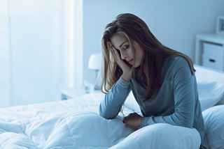 Depressed woman awake in the night, she is touching her forehead and suffering from insomnia